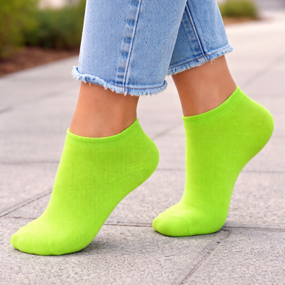 Person wearing bright green Ankle socks and blue jeans on a pavement.