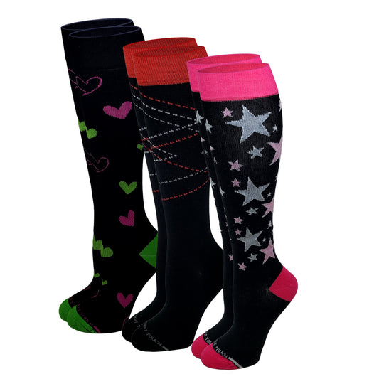 Three pairs of knee-high socks displayed together on a white background. The front pair is black with silver and pink stars, bright pink cuffs, and pink toes.