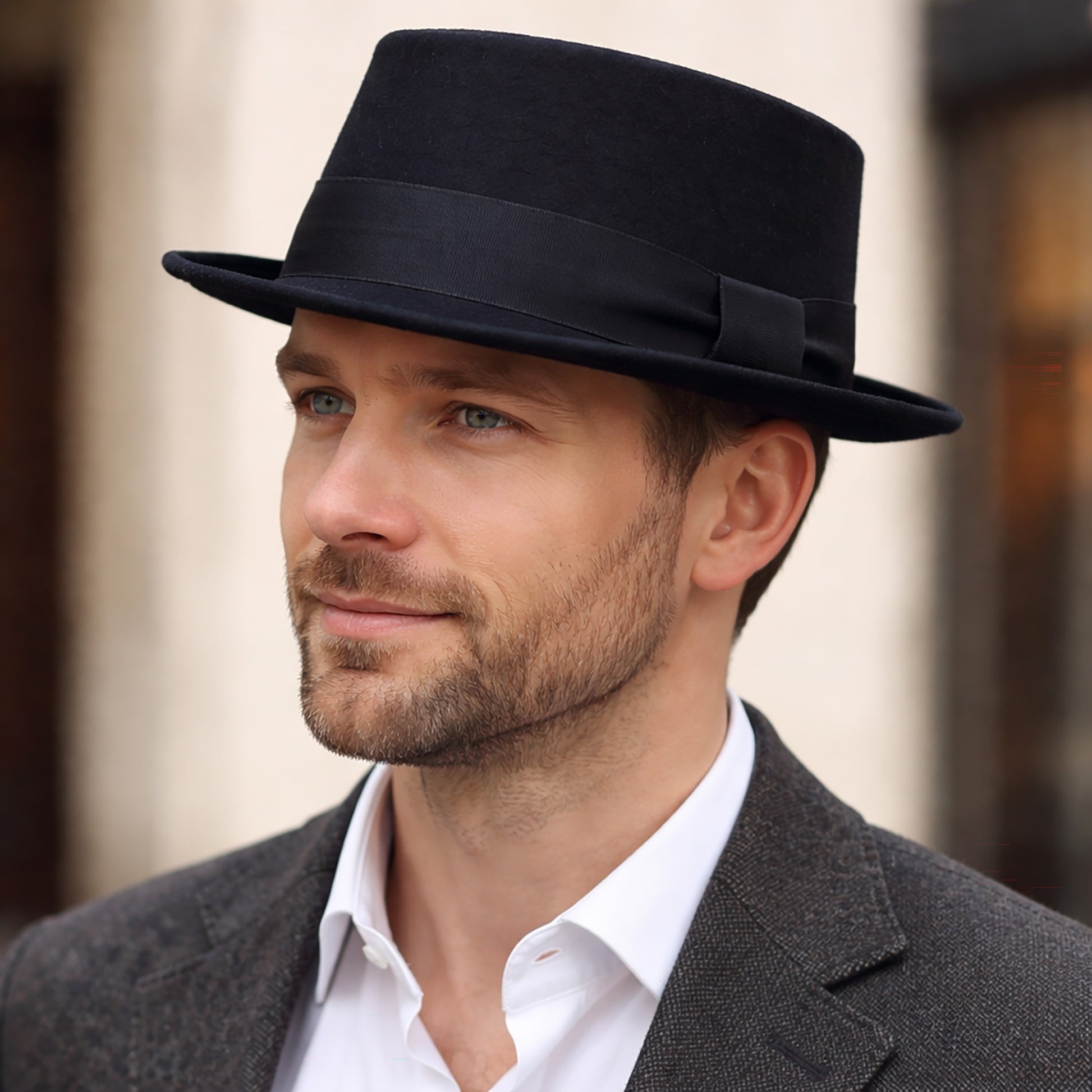 Man wearing a black fedora hat and gray suit with a blurred background